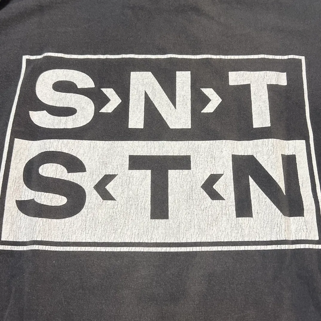SAINT Mxxxxxx S>N>T LS TEE/BLACK Autumn and winter new style S>N>T slogan crack printed long TEE, washed black S-XL Asut ready-made garments dyed, the whole piece sprayed with horse-hair spray, and then sprayed again to fade the color. The collar and cuffs are frayed. Many hangings are worn NEW VINTAGE. Heavy craftsmanship.